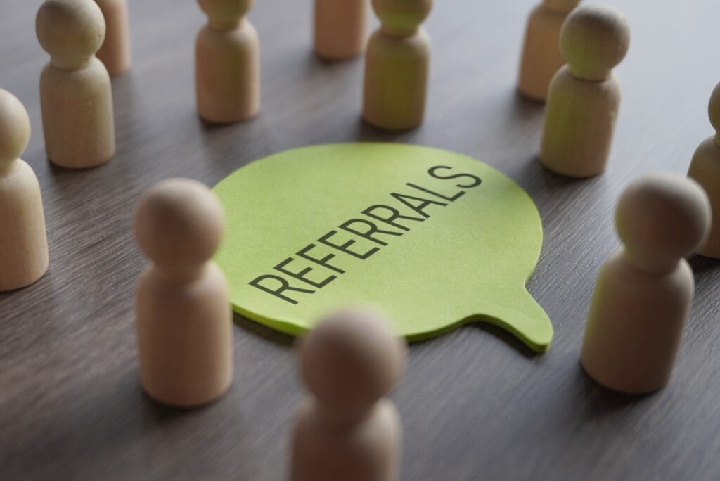 mastering the referral round in top networking meetings | a group of wooden figurines surrounding a speech bubble with text referrals.